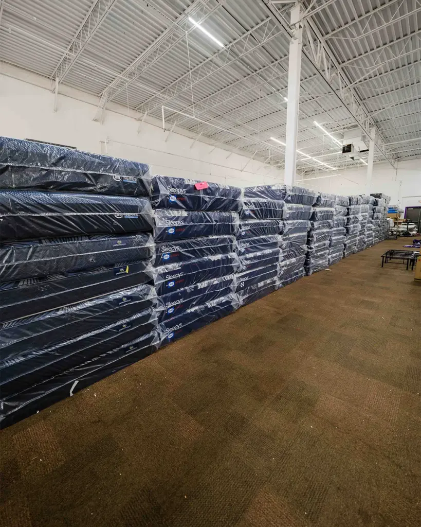 Wall of wrapped name brand mattresses at Compare Deals mattress outlet