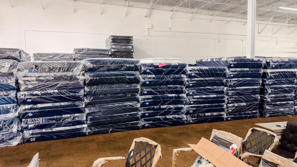 Wall of wrapped mattresses stacked at Compare Deals mattress outlet