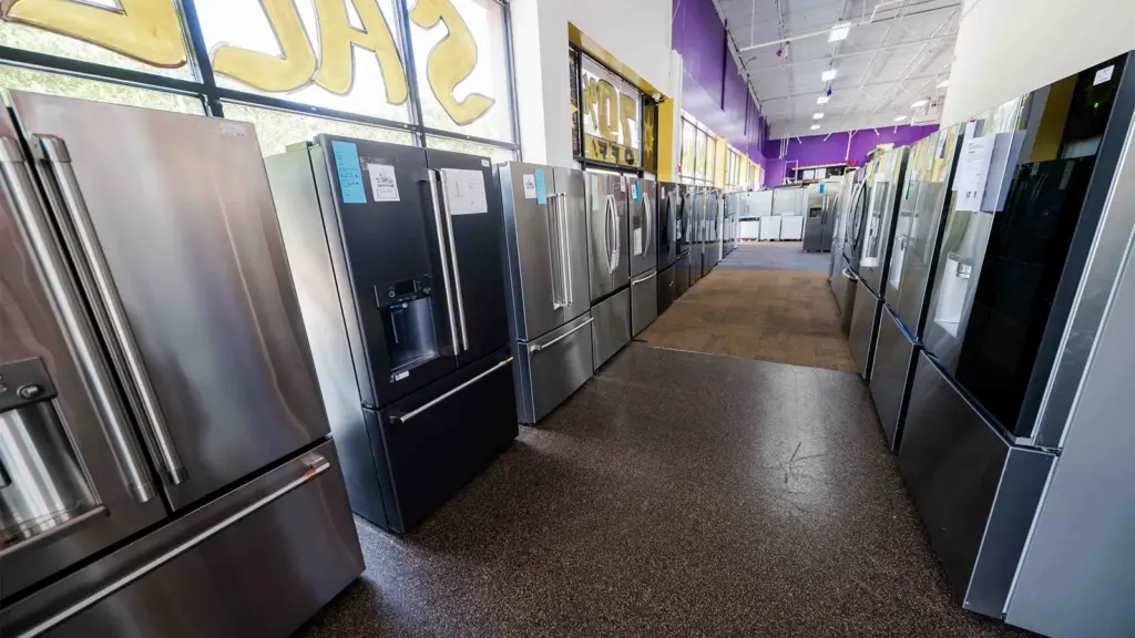 Aisle of discount stainless and black refrigerators at Compare Deals outlet