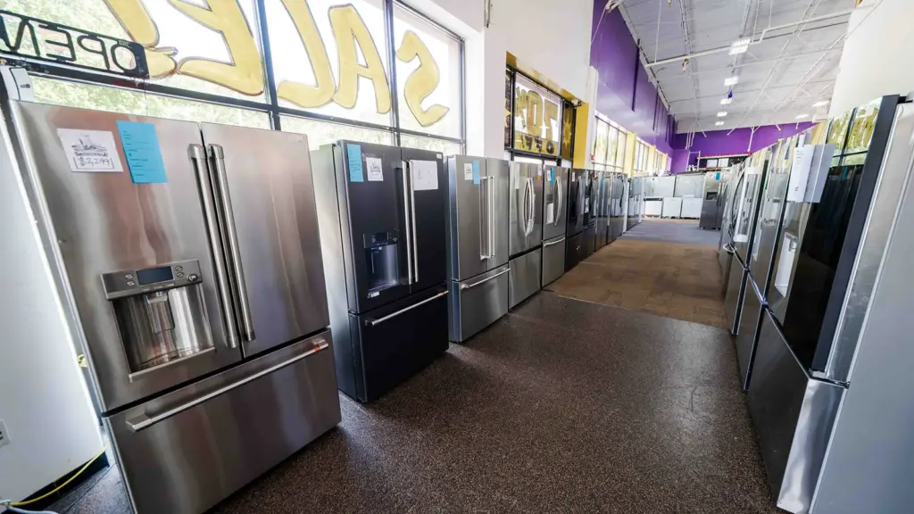 Row of stainless steel refrigerators at Compare Deals appliance outlet