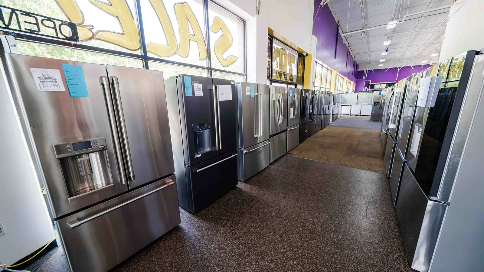 Row of stainless steel refrigerators at Compare Deals appliance outlet