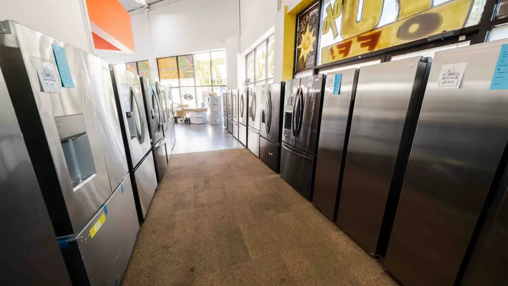 Discount refrigerators lining the aisle at Compare Deals appliance outlet